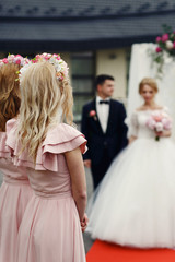 Canvas Print - Two beautiful elegant bridesmaids in pink dresses looking at mar