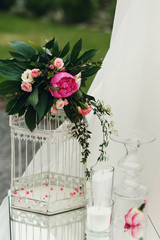 Beautiful white wedding cage decoration with flowers and leaves