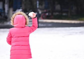 Cute girl ready to throw snowball during day, perspective from b