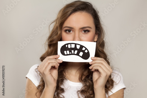 Fotografie, Obraz sad girl with a defective teeth painted on paper over her mouth