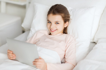 Poster - happy girl lying in bed with tablet pc at home