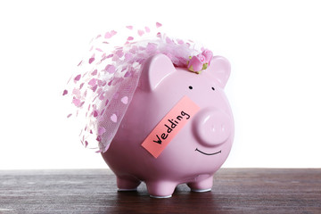 Piggy bank with wedding veil on wooden table, on white background