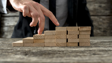 Wall Mural - Closeup of businessman walking his fingers up wooden steps