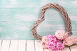 Postcard with pink  hyacinths  and  decorative heart on white  wooden  background against turquoise wall. Romantic background. Selective focus. Place for text.
