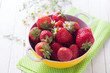 Fresh organic strawberry in bowl on towel on  white painted wood