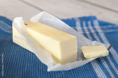 Fotografia, Obraz Stick of unwrapped butter on blue cloth