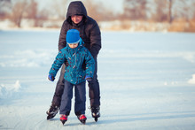 Father And Little Son Learning To Skate In Winter Snow.