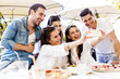 © NDABCREATIVITY - Group of young beautiful people sitting in a restaurant and taki