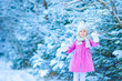 Adorable little girl with flashlight and candle in winter on Christmas outdoors
