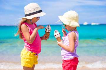 happy little girls eating ice-cream over summer beach background. people, children, friends and frie