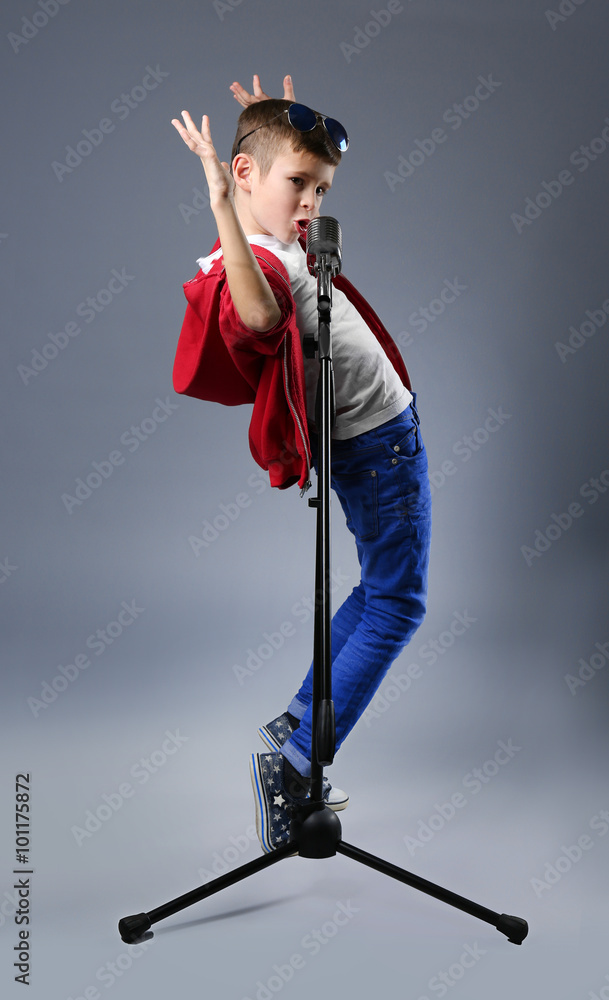 Little boy singing with microphone on a grey background
