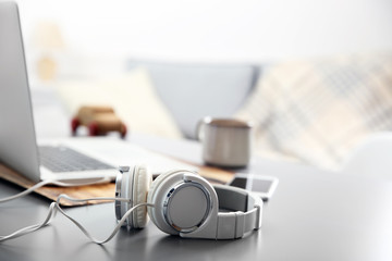 Wall Mural - Headphones, phone and laptop on white table against defocused background