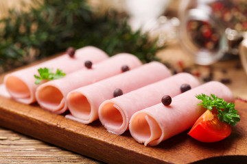 Delicious canned cooked ham on a wooden board with spices.