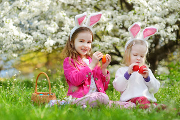 Wall Mural - Two adorable little sisters playing with Easter eggs on Easter day