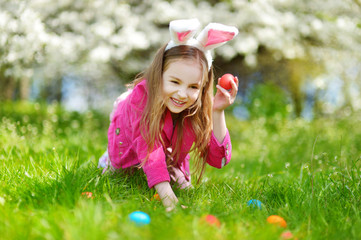 Wall Mural - Adorable little girl hunting for easter egg on Easter day