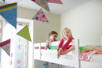 Two little sisters fooling around, playing and having fun in twin bunk bed