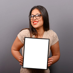 Portrait of smiling woman holding blank photo frame against gray