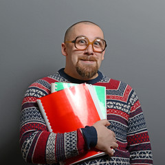 Wall Mural - Portrait of a nerd holding book with retro glasses against gray