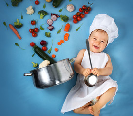 Baby boy in chef hat with cooking pan and vegetables