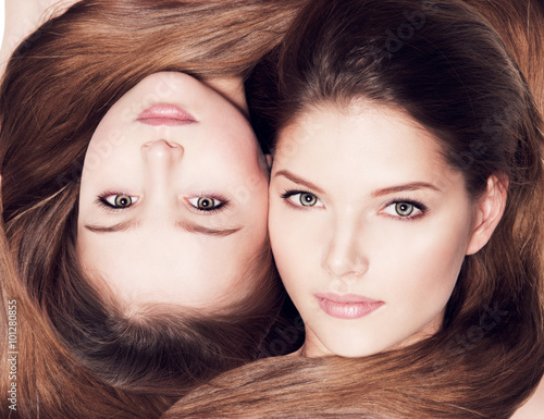 Naklejka ścienna Closeup faces of mother and little daughter 8 years with long