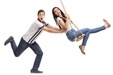 Delighted Man Pushing His Girlfriend On A Swing
