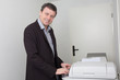 © OceanProd - Happy business man smiling near a copy machine at work