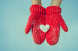 Female hands in knitted mittens with a vintage romantic red hear