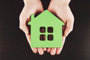 Sticker - Female hands holding house on wooden background