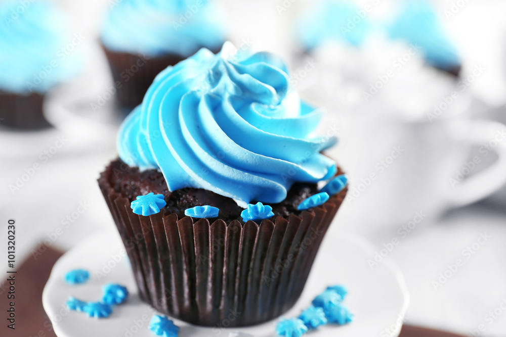 Delicious chocolate cupcake with blue cream on served table, close up