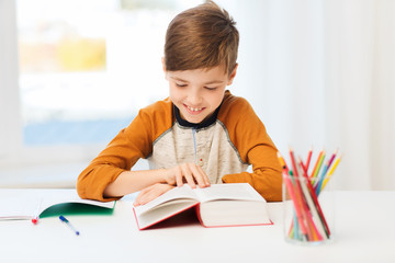 Wall Mural - smiling, student boy reading book at home