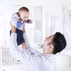 Dad lift up male infant in bedroom