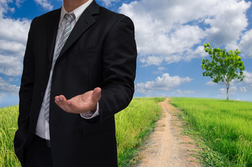 business man in black suite with welcome hand and blue sky backg