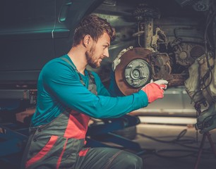 Canvas Print - Mechanic checking car brake system in a workshop