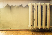 Old Cast Iron Radiators With Peeling Paint On The Wall