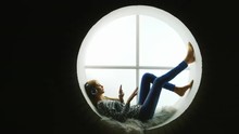 Attractive Woman Sitting At The Round Window, Listening To Music.