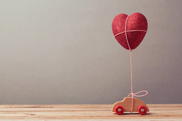 Wall Mural - Heart shape balloon and car toy on wooden table. Valentine's day concept.