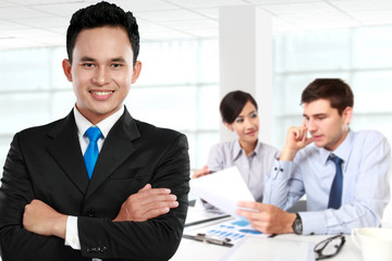 Poster - Young asian businessman, with his team behind. isolated in white