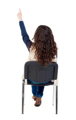 Wall Mural - back view of young beautiful  woman sitting on chair and pointin