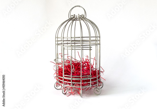 Fotografie, Obraz Close Steel Bird Cage with Pieces of Red Paper as Nest Isolated on White Backgro