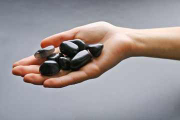 Poster - Woman holding semiprecious stones in her hand on dark grey background