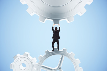 Canvas Print - Businessman pushing gears in the mechanism on a blue background