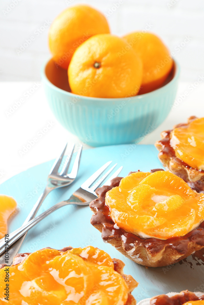 Sweet cakes with tangerines on table, close up