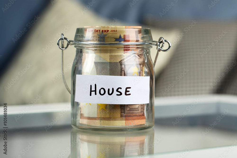 Glass jar with euro banknotes for house on a table