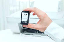Man Shows Black Ink Cartridge From White Printer