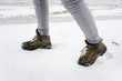 Female legs in hiking boots walking in snow