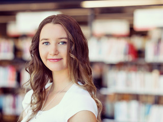 Wall Mural - Happy female student holding books at the library