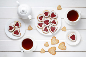 Wall Mural - Sweet heart cookies for Valentines day with teapot and two cups of tea composition on white wooden background