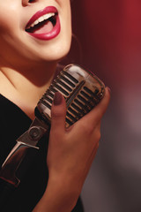 Portrait of beautiful singing woman on red background, close up