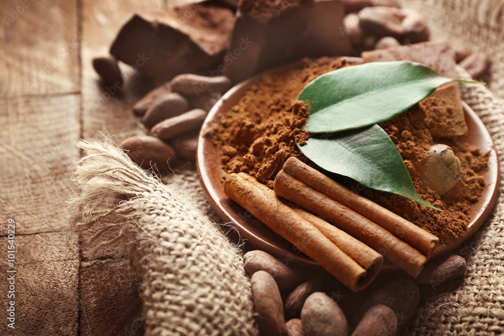 Bowl with aromatic cocoa powder and green leaf on a sacking, close up
