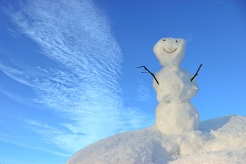  Freundlicher kleiner Schneemann vor blauem Himmel mit weißen Wolken 
